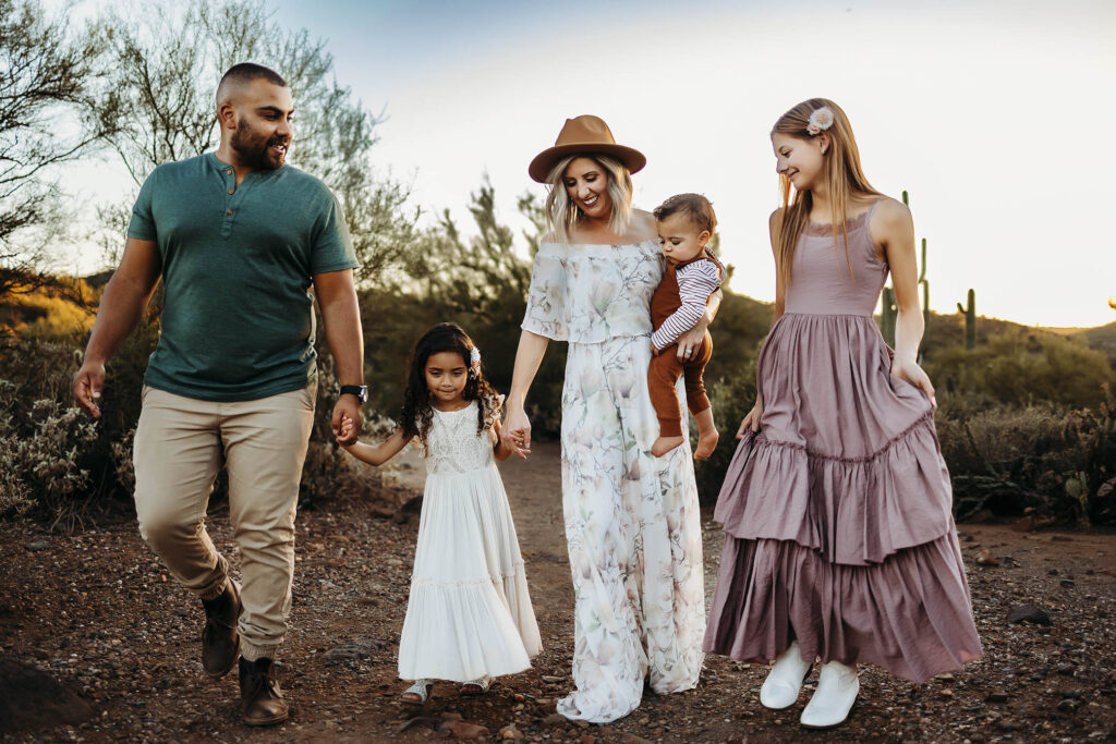 Family of five walking on a desert path amid cacti, wearing casual and semi-formal clothes.