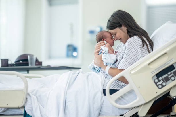 what to pack in your hospital bag, Mom holding newborn in hospital room